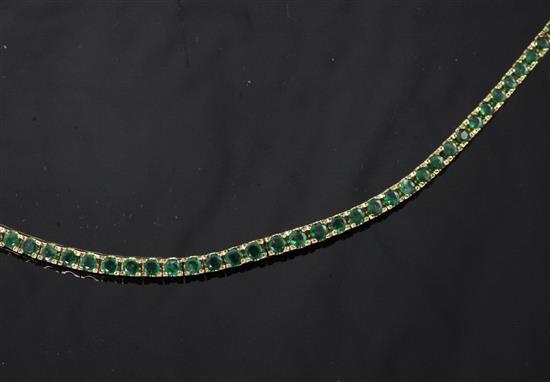 A 14ct gold and emerald line bracelet, 7in.